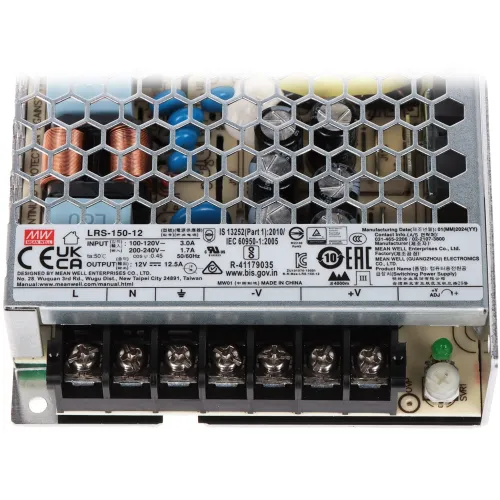 Zasilacz impulsowy z metalową obudową o strukturze plastra miodu, z widocznymi komponentami elektronicznymi wewnątrz. Na obudowie znajdują się etykiety z danymi technicznymi i certyfikatami.