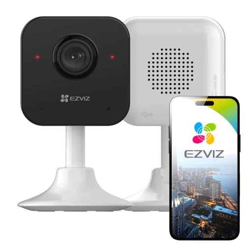 Na zdjęciu znajduje się czarna kamera domowa WiFi EZVIZ H1C na białej podstawce, obok której stoi smartfon z wyświetlonym logo EZVIZ i widokiem miasta. W tle widać tylną część kamery z otworami wentylacyjnymi.