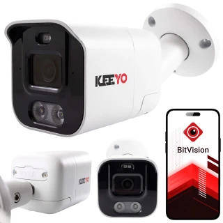 Na zdjęciu znajduje się biała kamera tubowa marki Keeyo z czarnym panelem frontowym, zamontowana na ścianie. Obok kamery widoczny jest smartfon z aplikacją BitVision na ekranie.