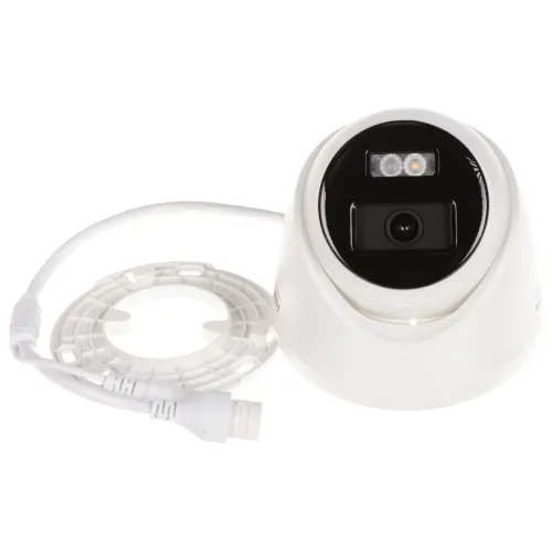 Biała kamera monitoringu z czarnym panelem przednim i dwoma diodami LED jest pokazana obok białego pierścienia zaciskowego i kabla. Kamera ma kompaktowy, kopułowy kształt i jest przeznaczona do montażu sufitowego lub ściennego.