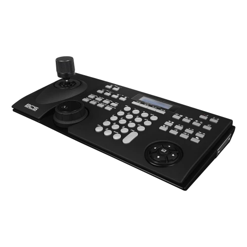 Czarna klawiatura sieciowa BCS z wieloma przyciskami, joystickiem i pokrętłem, przeznaczona do zarządzania systemami monitoringu. Urządzenie posiada wyświetlacz LCD oraz ergonomiczny układ przycisków.