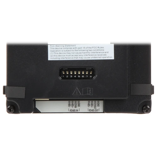 Zdjęcie przedstawia panel konfiguracyjny z ośmioma przełącznikami DIP umieszczonymi na czarnym tle. Obok przełączników znajduje się etykieta z informacjami o zgodności z przepisami FCC.