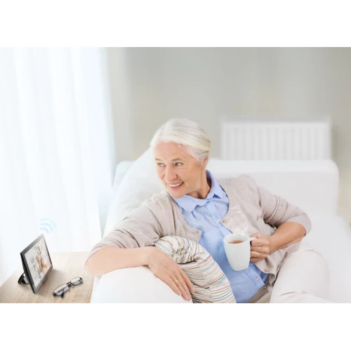 Sterownik gestem Fibaro Swipe to eleganckie urządzenie w formie ramki na zdjęcia, które umożliwia bezdotykowe sterowanie inteligentnym domem. Produkt jest dyskretnie umieszczony na stoliku obok okularów, co podkreśla jego nowoczesny i funkcjonalny design.