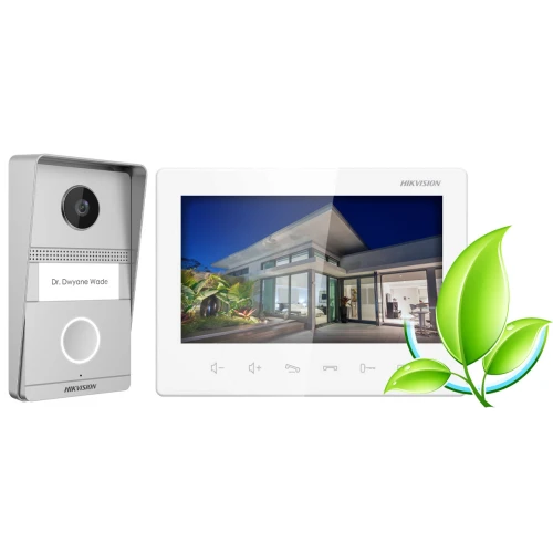 Na zdjęciu znajduje się wideodomofon Hikvision z panelem zewnętrznym i wewnętrznym monitorem, na którym wyświetlany jest obraz nowoczesnego domu. Obok urządzenia widoczna jest grafika przedstawiająca zielony liść.