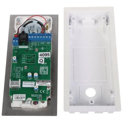 Zdjęcie przedstawia wnętrze obudowy elektronicznego urządzenia z widoczną płytką drukowaną i podłączonymi przewodami. Obok znajduje się biała, plastikowa obudowa z miejscem na montaż.