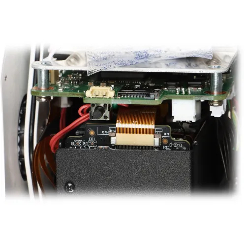 Zdjęcie przedstawia wnętrze urządzenia elektronicznego z widocznymi płytkami drukowanymi, przewodami i złączami. W centralnej części znajduje się taśma łącząca różne komponenty.