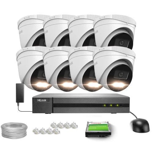 Na zdjęciu znajduje się zestaw do monitoringu, składający się z ośmiu białych kamer kopułkowych, rejestratora, dysku twardego, kabla oraz złączy. Kamery są ustawione w dwóch rzędach nad rejestratorem, a obok nich widoczna jest mysz komputerowa.