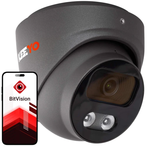 Na zdjęciu znajduje się czarna kamera monitoringu z logo "KEEYO" oraz smartfon z aplikacją "BitVision" na ekranie. Kamera ma nowoczesny design i jest skierowana w stronę widza, a aplikacja na telefonie pokazuje interfejs związany z monitoringiem.